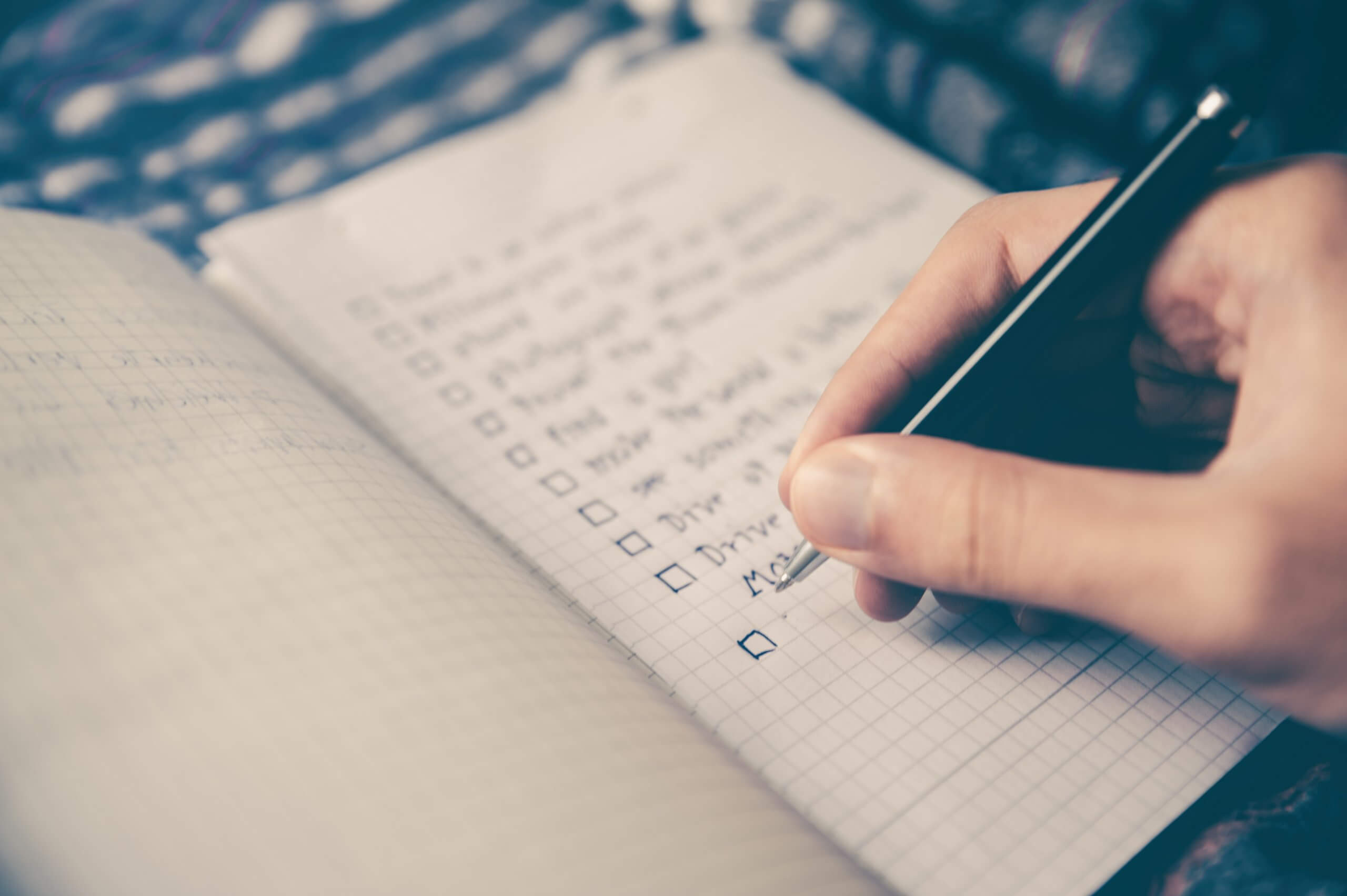 Checklist in a notebook, hand with pen checking off items