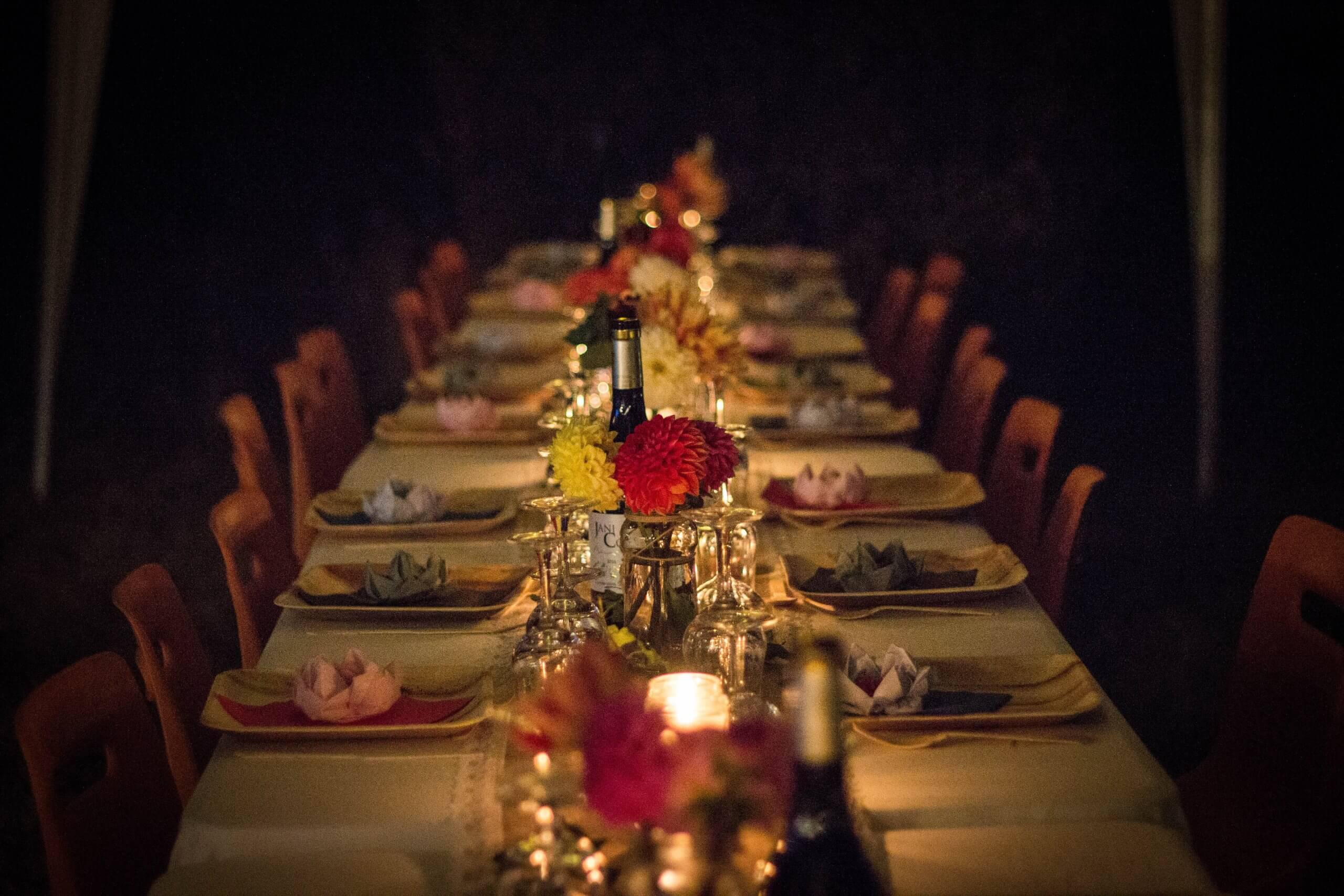 A candlelit table with rows of place settings
